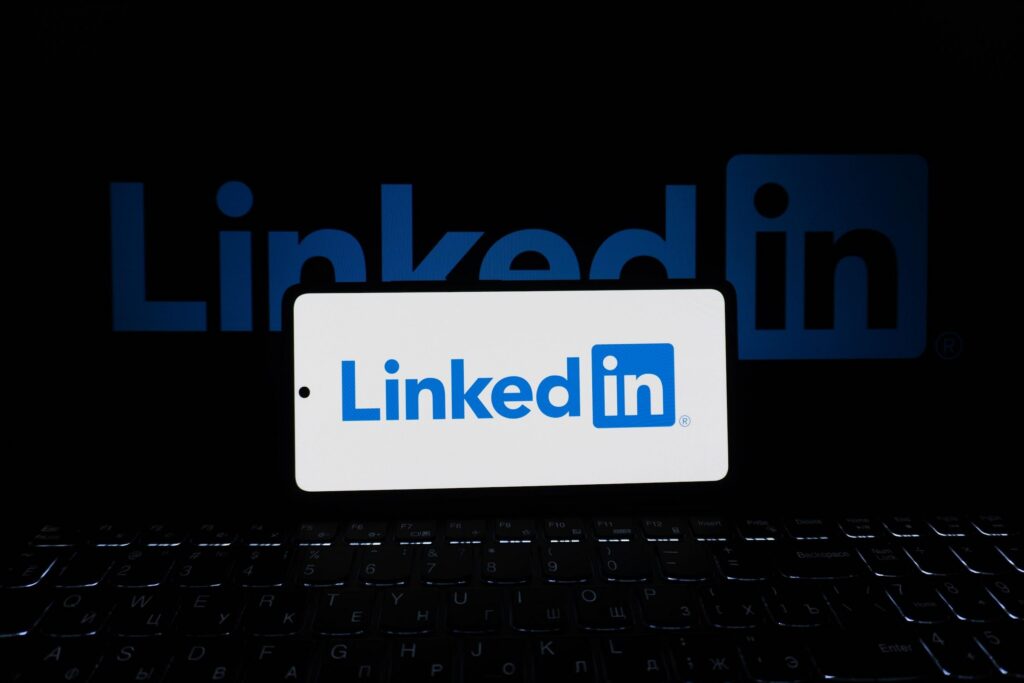Logo LinkedIn affiché sur smartphone posé sur un clavier d'ordinateur pour la gestion de campagnes publicitaires LinkedIn Ads