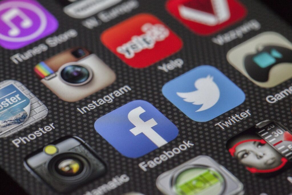 Écran de smartphone affichant les icônes des réseaux sociaux Facebook, Instagram et Twitter pour la gestion de campagnes social ads