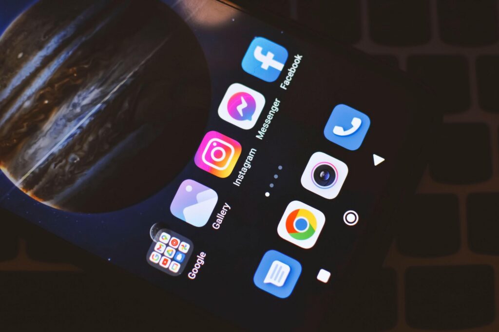 Écran de smartphone affichant les applications réseaux sociaux Instagram, Facebook et Messenger pour une agence de community management