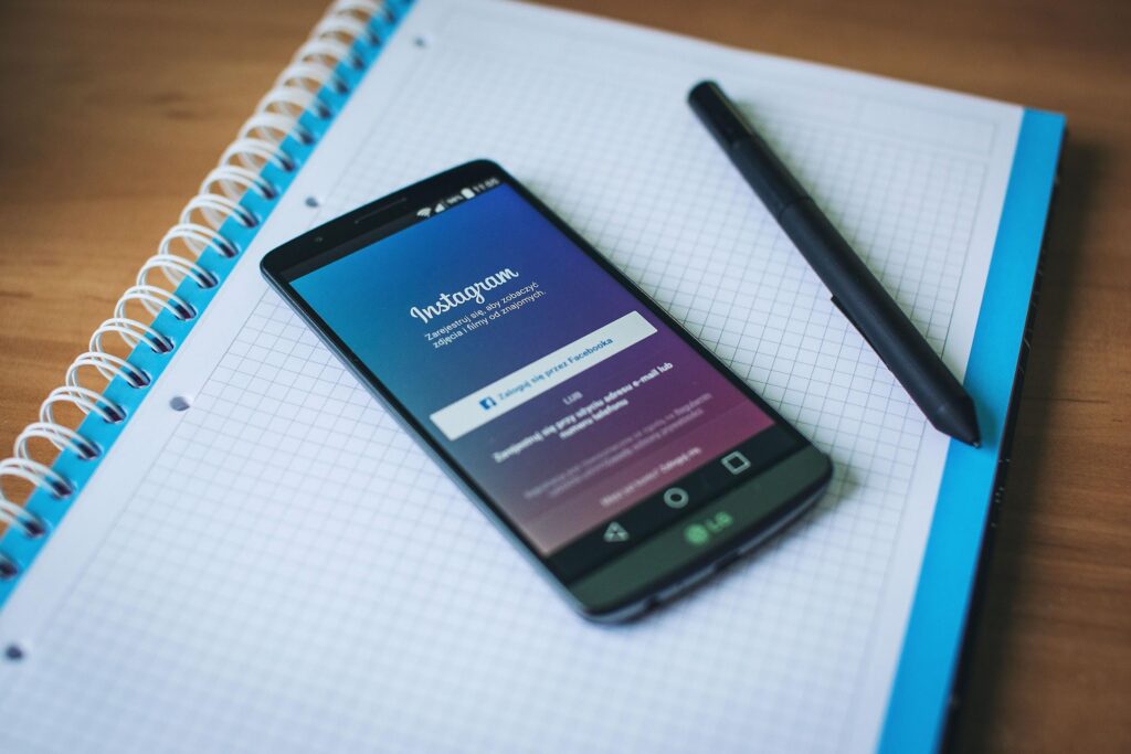 Smartphone affichant l'application Instagram posé sur un carnet de notes pour la gestion de campagnes publicitaires Instagram Ads